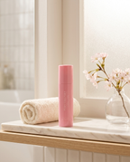 PDRN Collagen Glow Balm on a bathroom shelf with towel and cherry blossom in morning light