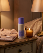 Tighten and Smooth Belly Cream jar on a bedside table with candle in cozy evening light